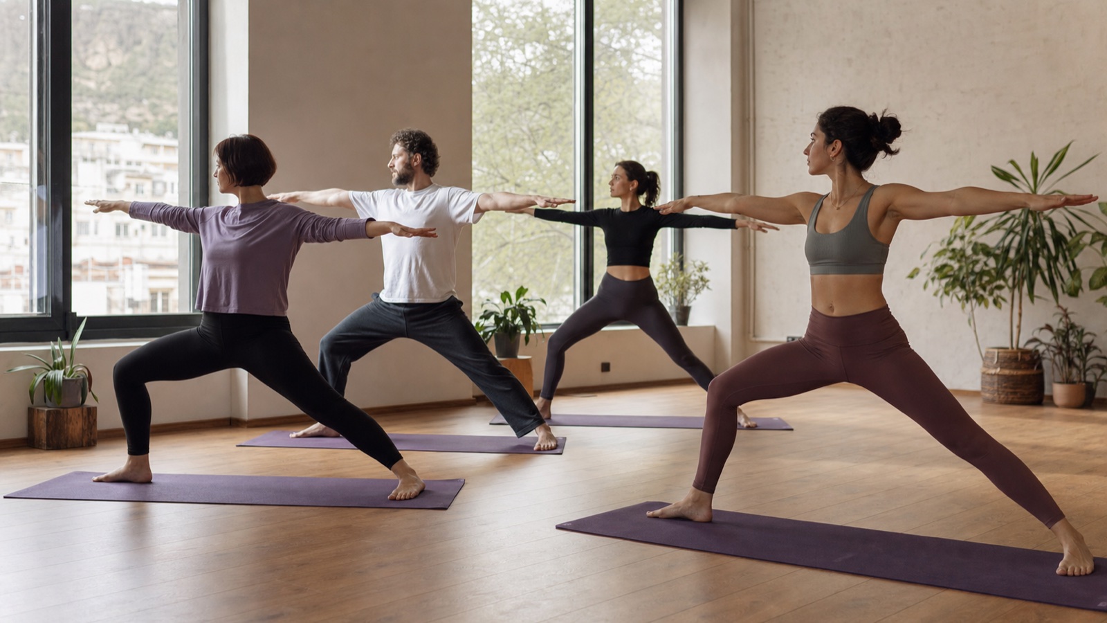 Four adult beginners along with the instructor perform the yogi warrior pose in the Tbilisi studio